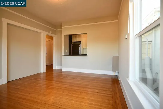 a view of an empty room with wooden floor and a window