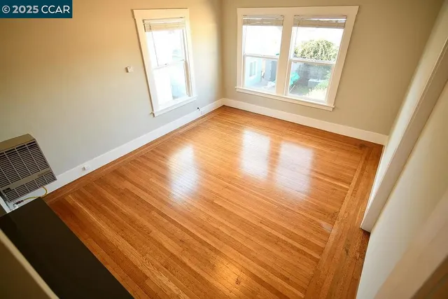 a view of an empty room with wooden floor and a window