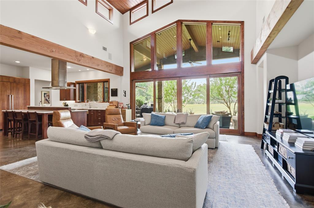 1138 Bancroft Road Keller, TX 76248 - Photo 9 of 39 Vaulted ceiling with exposed wood beams, expansive floor-to-ceiling windows, wood-finish flooring, a contemporary kitchen with a large island, and built-in cabinetry