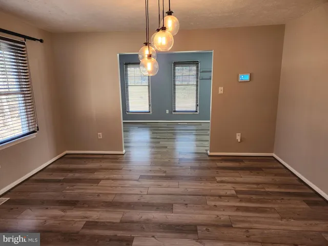 a view of an empty room with wooden floor and fan