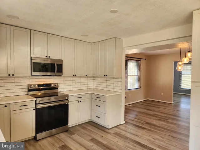 a kitchen with stainless steel appliances white cabinets and a stove top oven