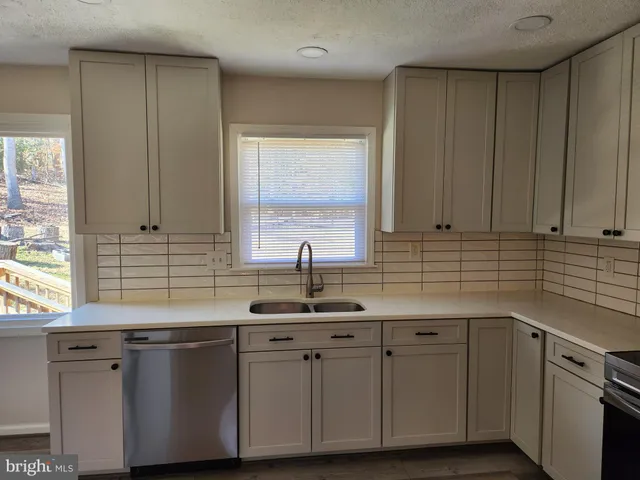 a kitchen with stainless steel appliances granite countertop white cabinets sink and dishwasher with wooden floor