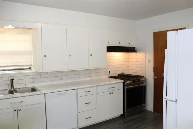 a kitchen with granite countertop white cabinets and white appliances