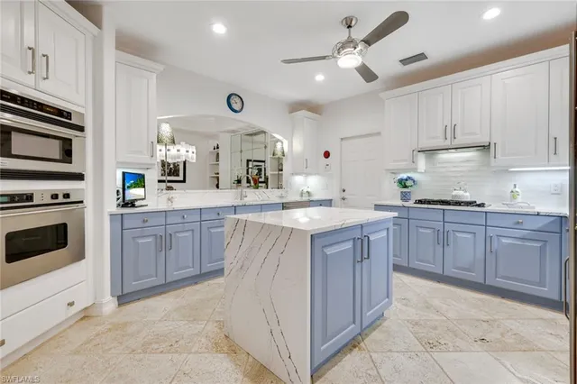a kitchen with kitchen island granite countertop a sink counter top space appliances and cabinets