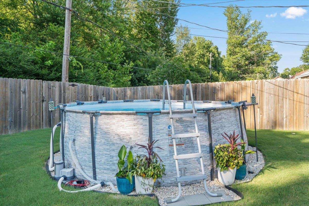 7300 Country Side Road Memphis, TN 38133 - Photo 21 of 22 Above-ground pool featuring a stone-look exterior, surrounding gravel landscaping, and a wooden privacy fence