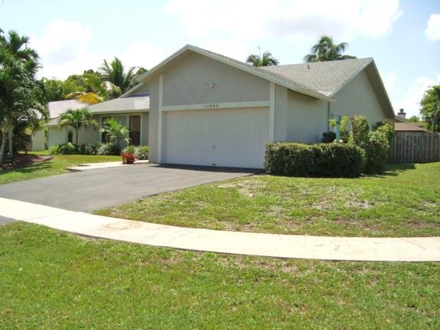 11460 Woodchuck Drive Boca Raton, FL 33428 - Photo 4 of 32 a view of a house with a yard and garage
