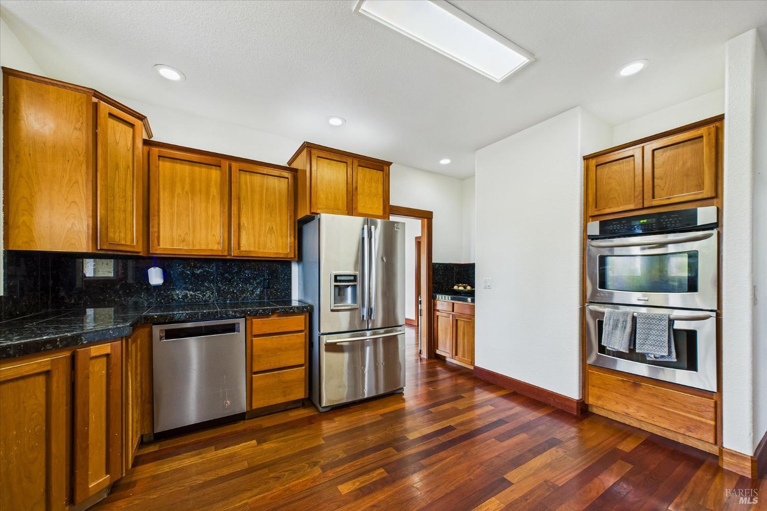 1150 Dinsmore Ranch Road Rio Dell, CA 95562 - Photo 29 of 71 a kitchen with stainless steel appliances granite countertop a refrigerator a stove and a wooden floor