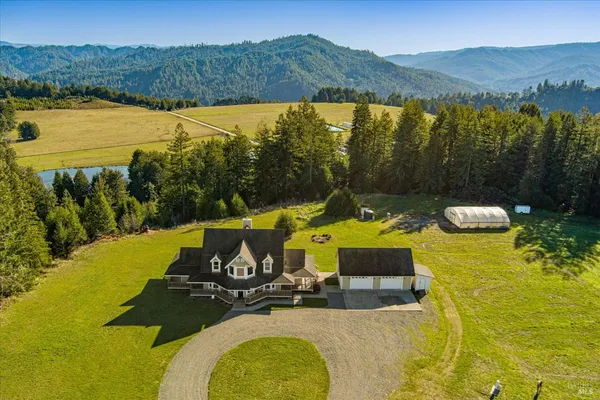 a front view of a house with swimming pool lawn chairs and large trees