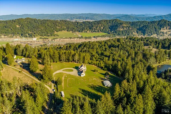 a view of a big house with a big yard and large trees