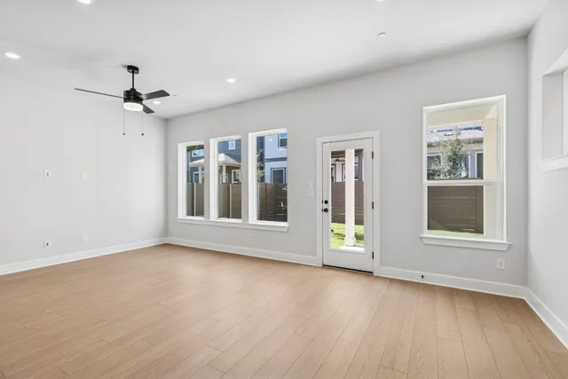a view of an empty room with a window and wooden floor