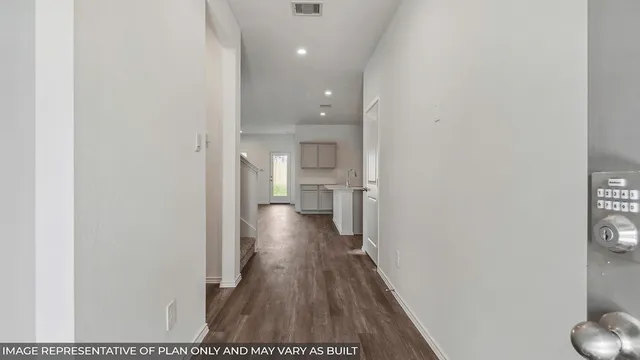 a view of a hallway with wooden floor and a bathroom