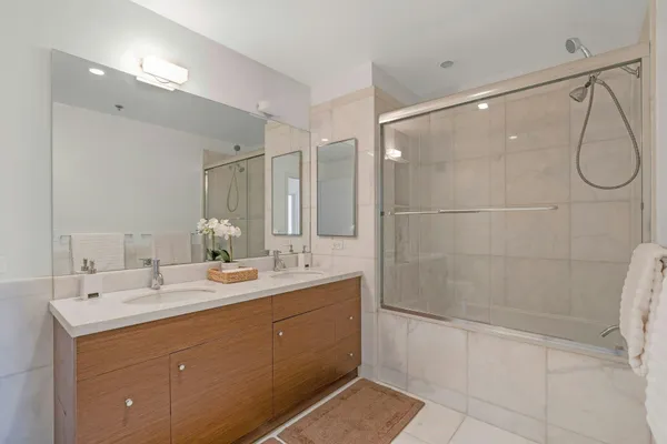 a bathroom with a double vanity sink mirror and shower