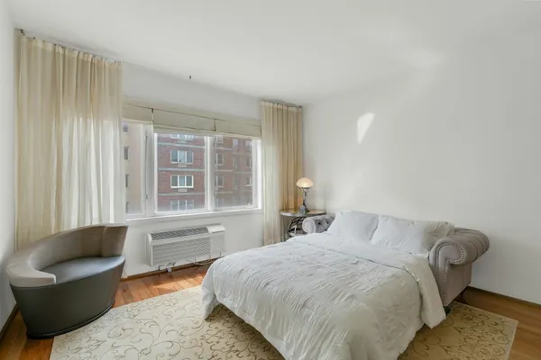 a bedroom with a bed chair and a large window