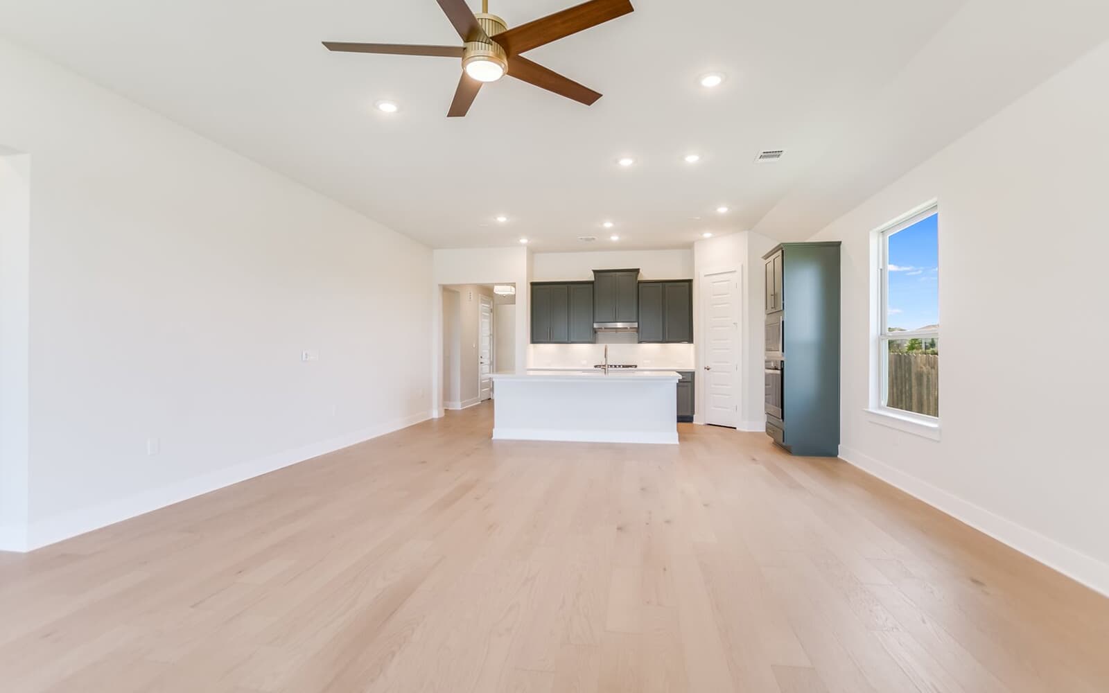 9000 The Ravine Way Austin, TX 78744 - Photo 2 of 17 Unfurnished living room featuring light wood-style flooring, a ceiling fan, and recessed lighting