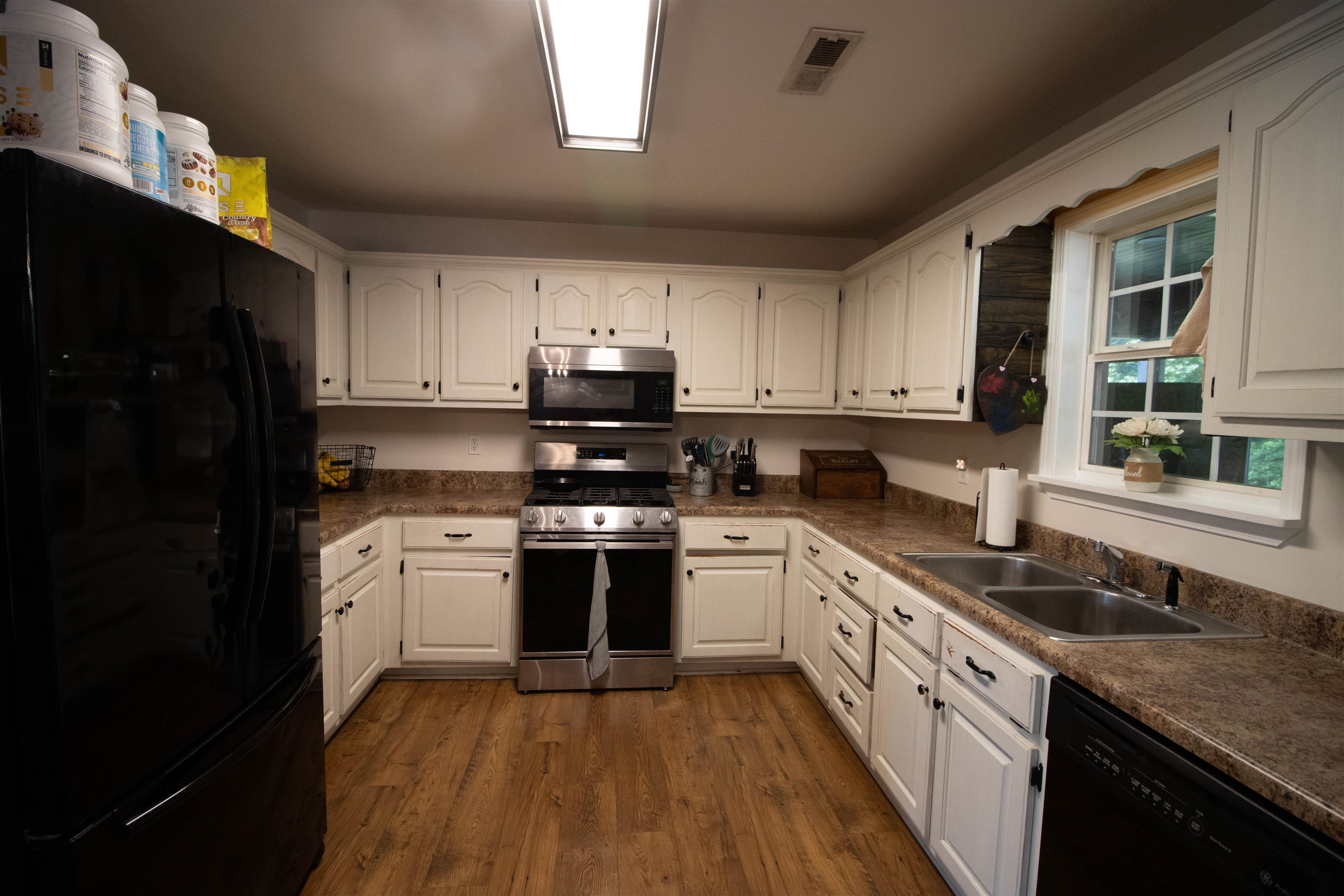 120 Craig Road Ripley, TN 38063 - Photo 10 of 38 Kitchen with extensive white cabinetry, wood-finish flooring, and a stainless steel oven/range with an overhead microwave