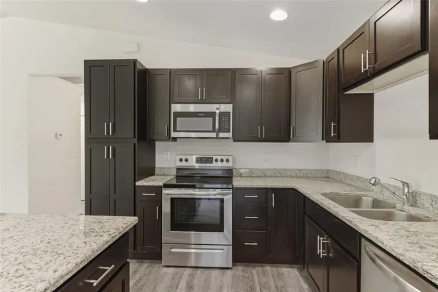 a kitchen with stainless steel appliances granite countertop a sink stove and refrigerator