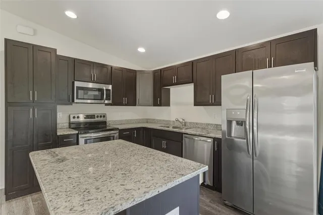 a kitchen with kitchen island a refrigerator and a sink