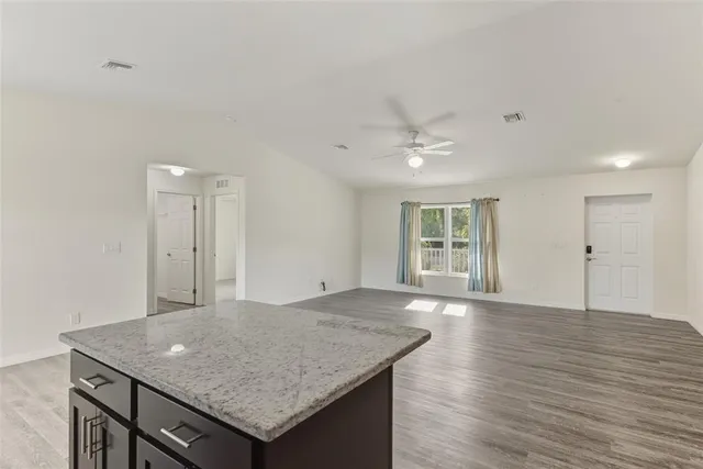 a view of a kitchen island a sink wooden floor and a living room