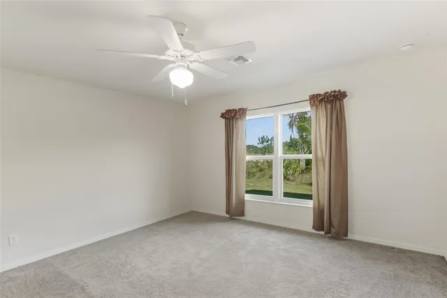 an empty room with a window and ceiling fan