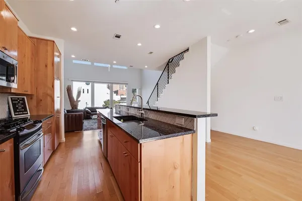 a kitchen with stainless steel appliances granite countertop a sink a stove and a wooden floors