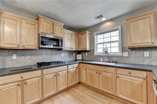 a kitchen with stainless steel appliances kitchen island granite countertop a refrigerator a oven a stove and a wooden floors