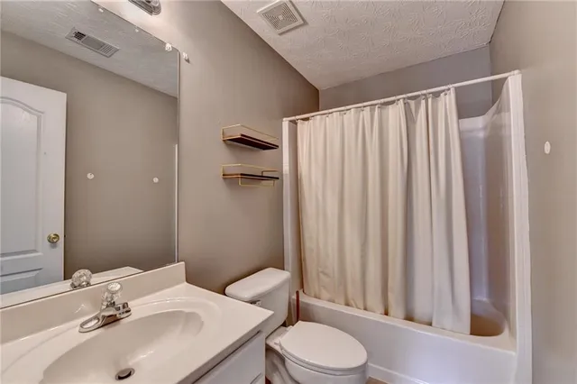 an empty room with chandelier fan and windows