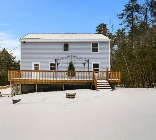 a view of a blue house with snow on the side of the road