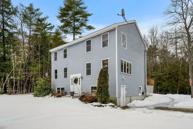 a front view of house with yard and trees in the background