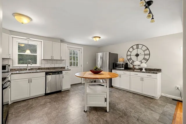 a open kitchen with stainless steel appliances granite countertop a stove a sink dishwasher and white cabinets with wooden floor