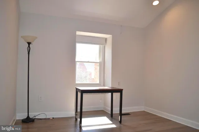 a view of an empty room with a window and wooden floor