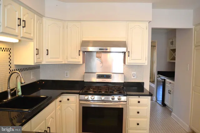a kitchen with granite countertop a stove a sink and a refrigerator