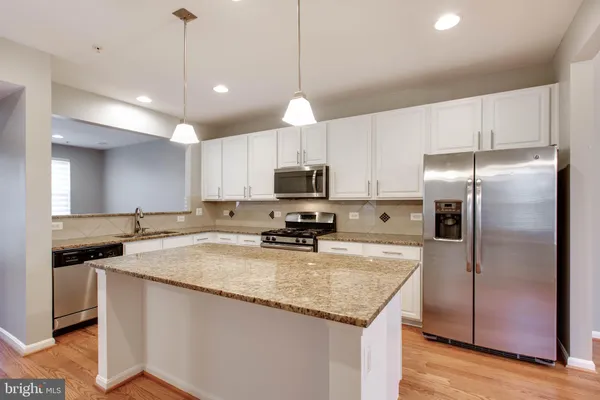 a kitchen with kitchen island granite countertop a center island and stainless steel appliances