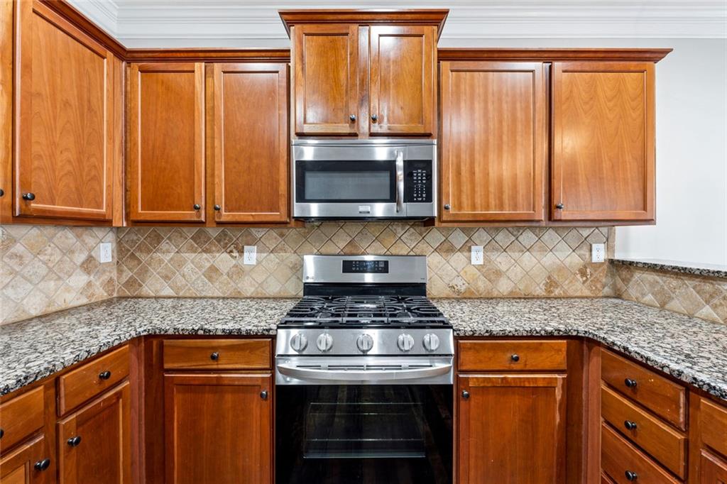 3184 Buck Way Alpharetta, GA 30004 - Photo 11 of 48 a kitchen with granite countertop a stove top oven cabinetry a sink and a window