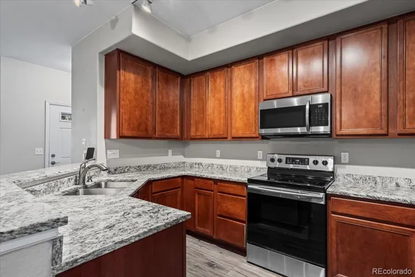 a kitchen with stainless steel appliances granite countertop wooden cabinets a stove top oven a sink and dishwasher