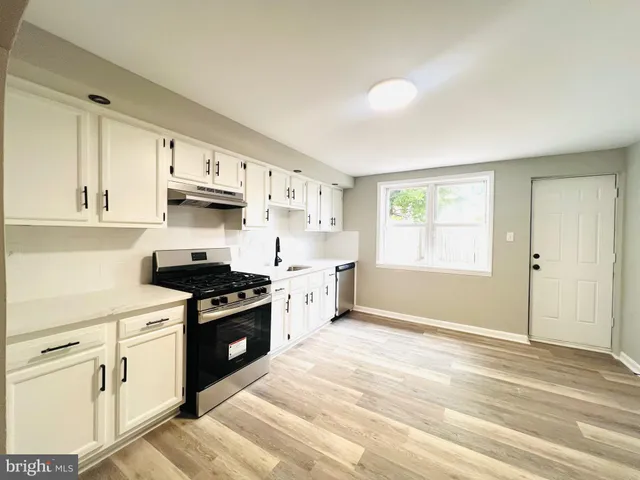 a kitchen with stainless steel appliances granite countertop a stove a sink and white cabinets