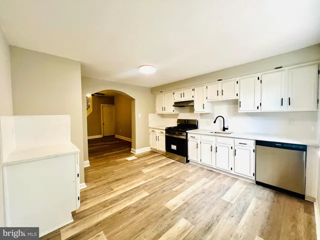 a kitchen with stainless steel appliances a stove a sink and white cabinets