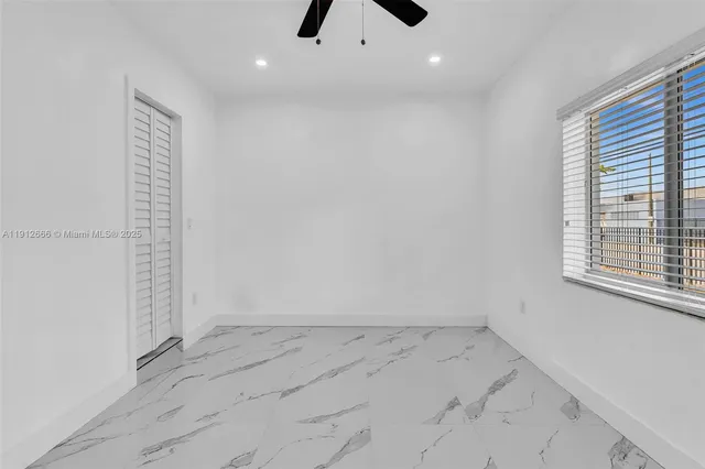 an empty room with ceiling fan and window