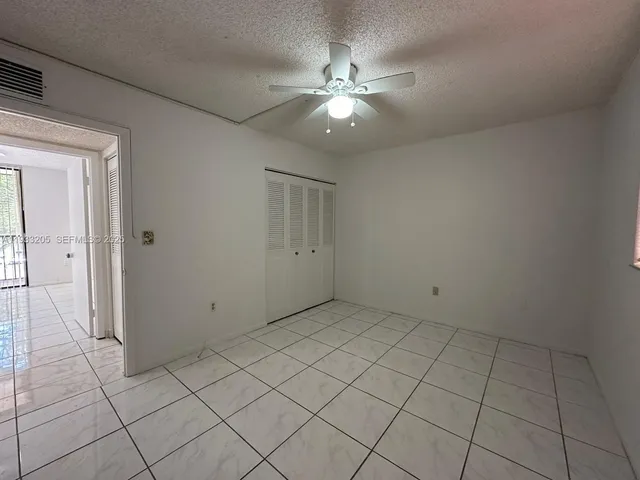 an empty room with a chandelier fan and glass door