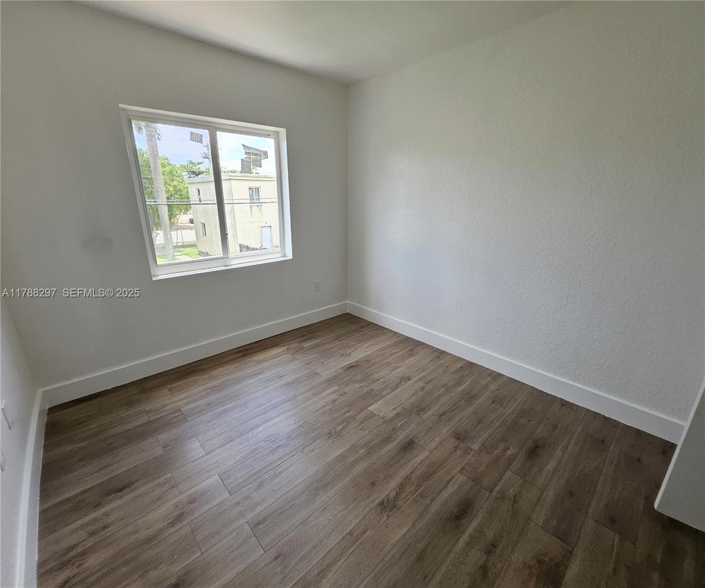 450 Northwest 84th Street, Unit 450 Miami, FL 33150 - Photo 11 of 28 an empty room with wooden floor and windows