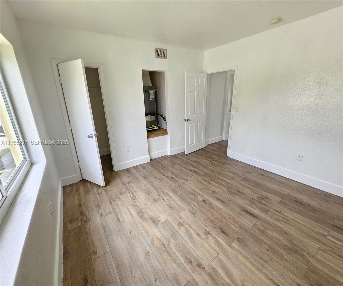 450 Northwest 84th Street, Unit 450 Miami, FL 33150 - Photo 18 of 28 a view of empty room with wooden floor and window