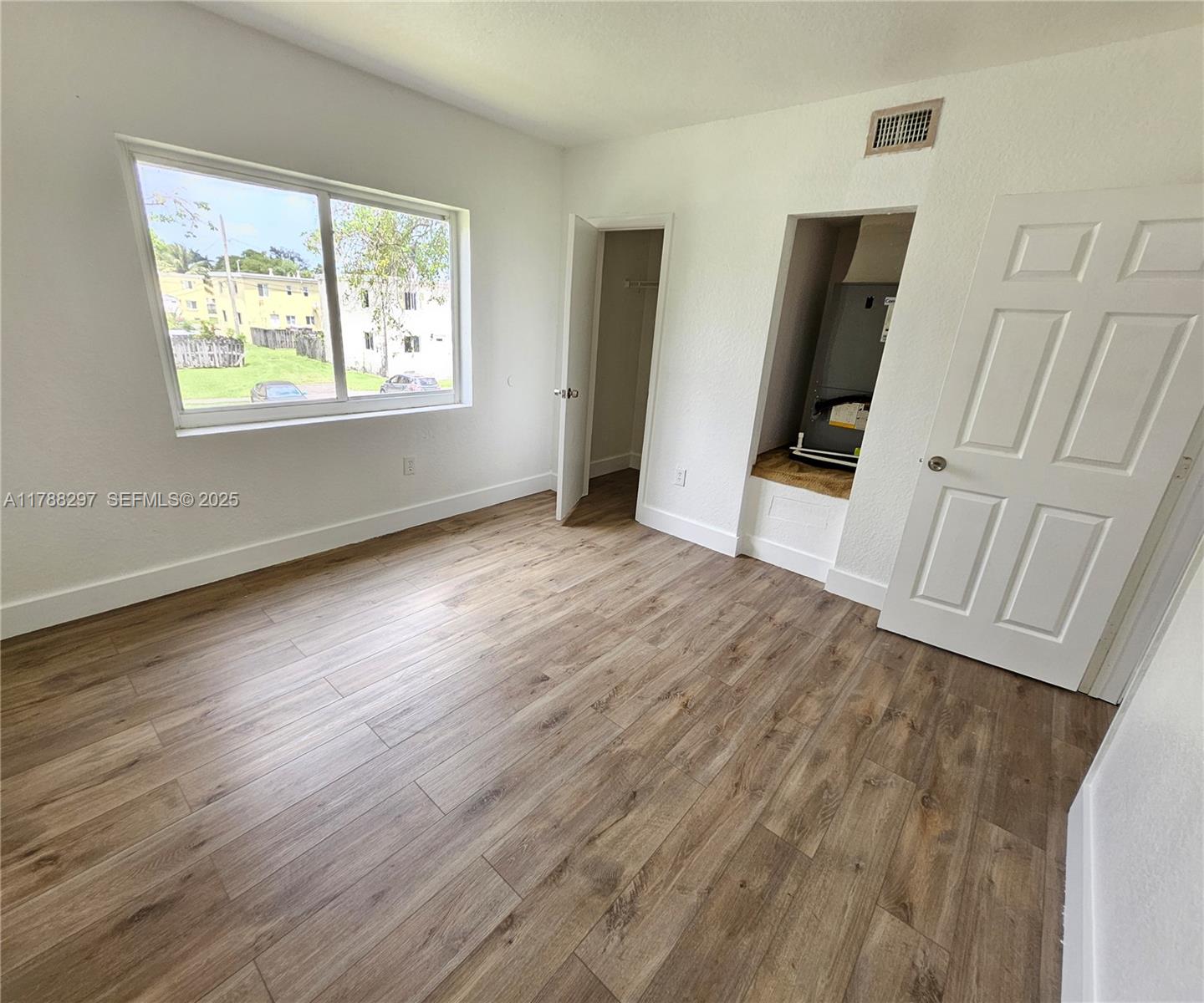 450 Northwest 84th Street, Unit 450 Miami, FL 33150 - Photo 19 of 28 a view of an empty room with wooden floor and a window