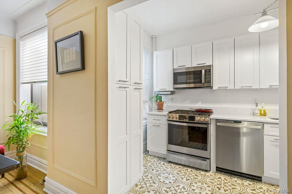 43 Calton Road, Unit 5C New Rochelle, NY 10804 - Photo 11 of 32 Kitchen featuring stainless steel appliances, white cabinetry, and hanging light fixtures