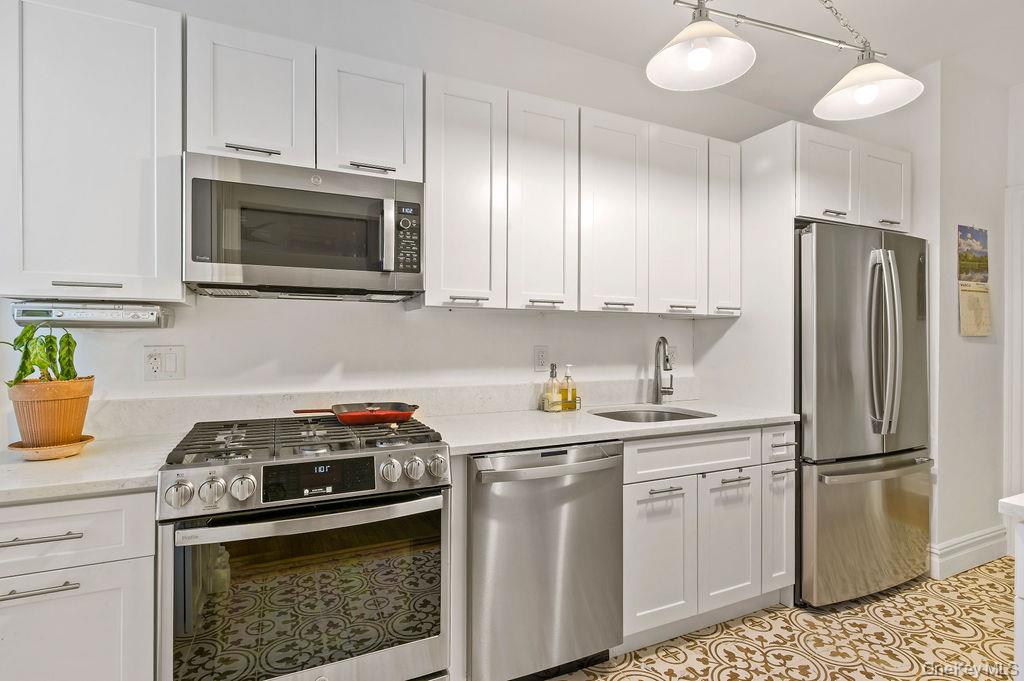 43 Calton Road, Unit 5C New Rochelle, NY 10804 - Photo 9 of 32 Kitchen with appliances with stainless steel appliances, white cabinets, light stone counters.
