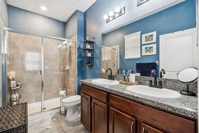 a bathroom with a granite countertop sink toilet a mirror a vanity and shower