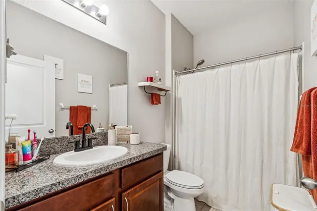 a bathroom with a granite countertop sink and a mirror with toilet