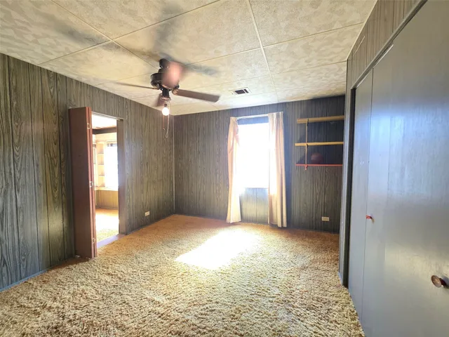 a view of a livingroom with a chandelier fan and windows