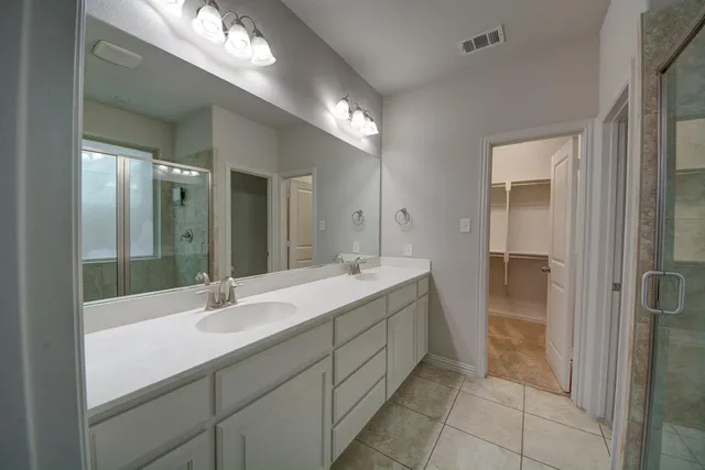 a bathroom with a double vanity sink a mirror and a shower