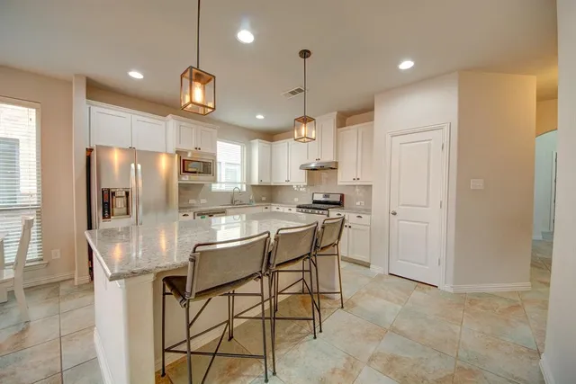 a kitchen with stainless steel appliances kitchen island granite countertop a refrigerator a stove a kitchen island with a dining table and chairs