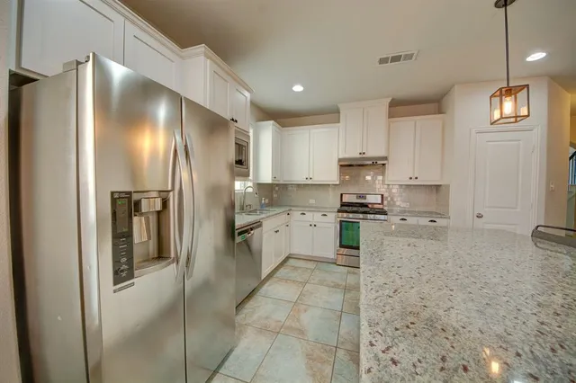 a kitchen with granite countertop stainless steel appliances and refrigerator