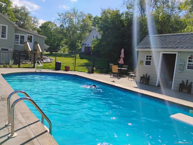 a view of swimming pool with lounge chair and dinning table under an umbrella